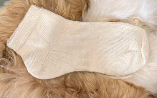 cream alpaca trainer sock on a fluffy beige surface