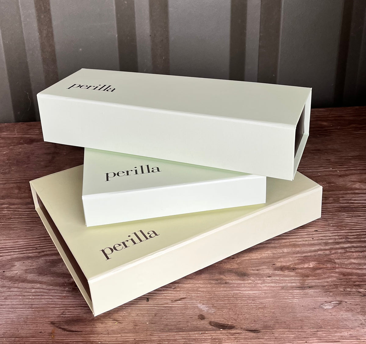 Three 'perilla' branded boxes stacked on a wooden surface