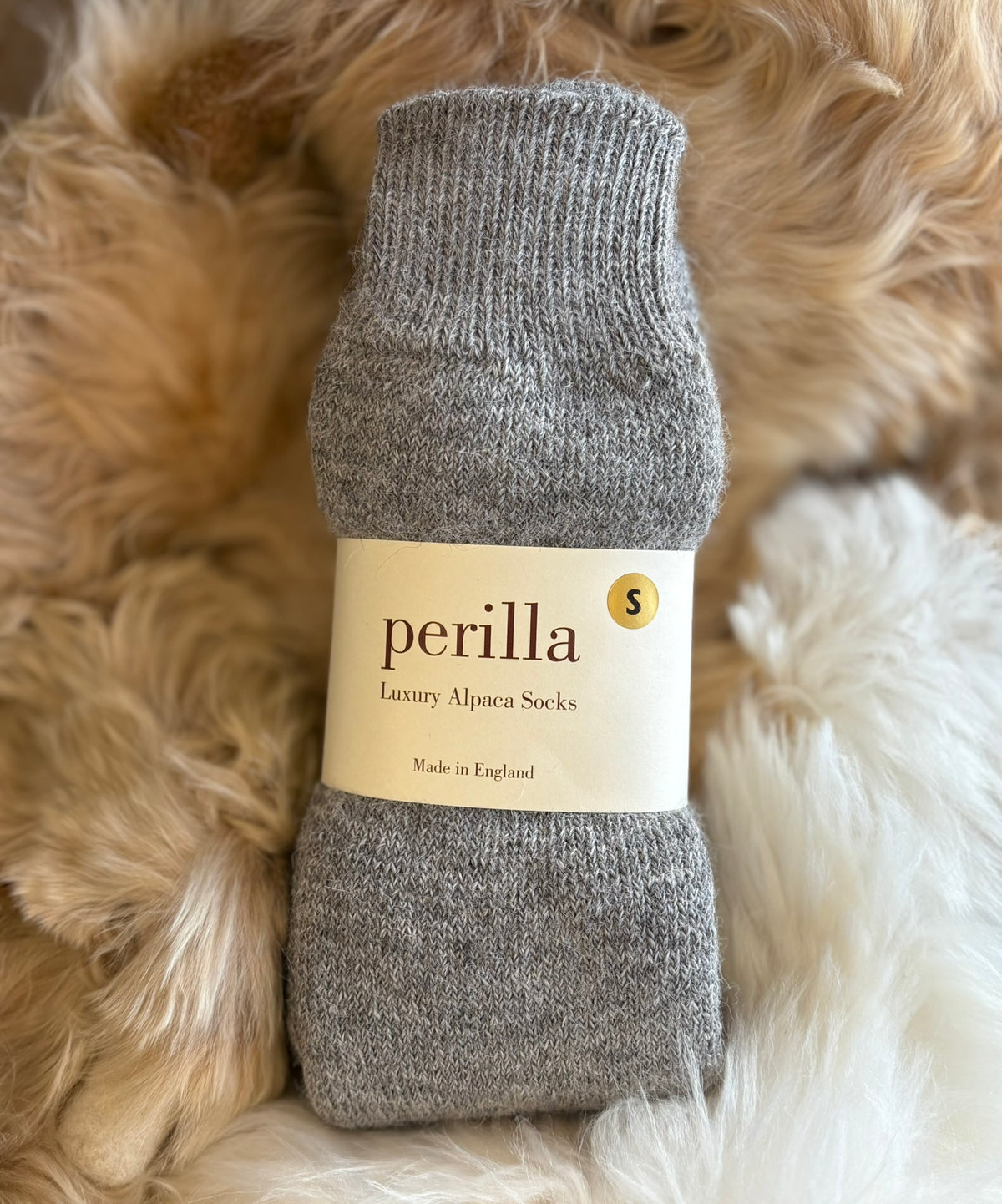 Gray alpaca walking sock with 'perilla' label on a fluffy beige background