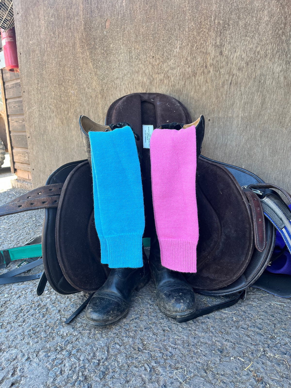 Saddle with pink and blue long activity alpaca socks on a textured surface