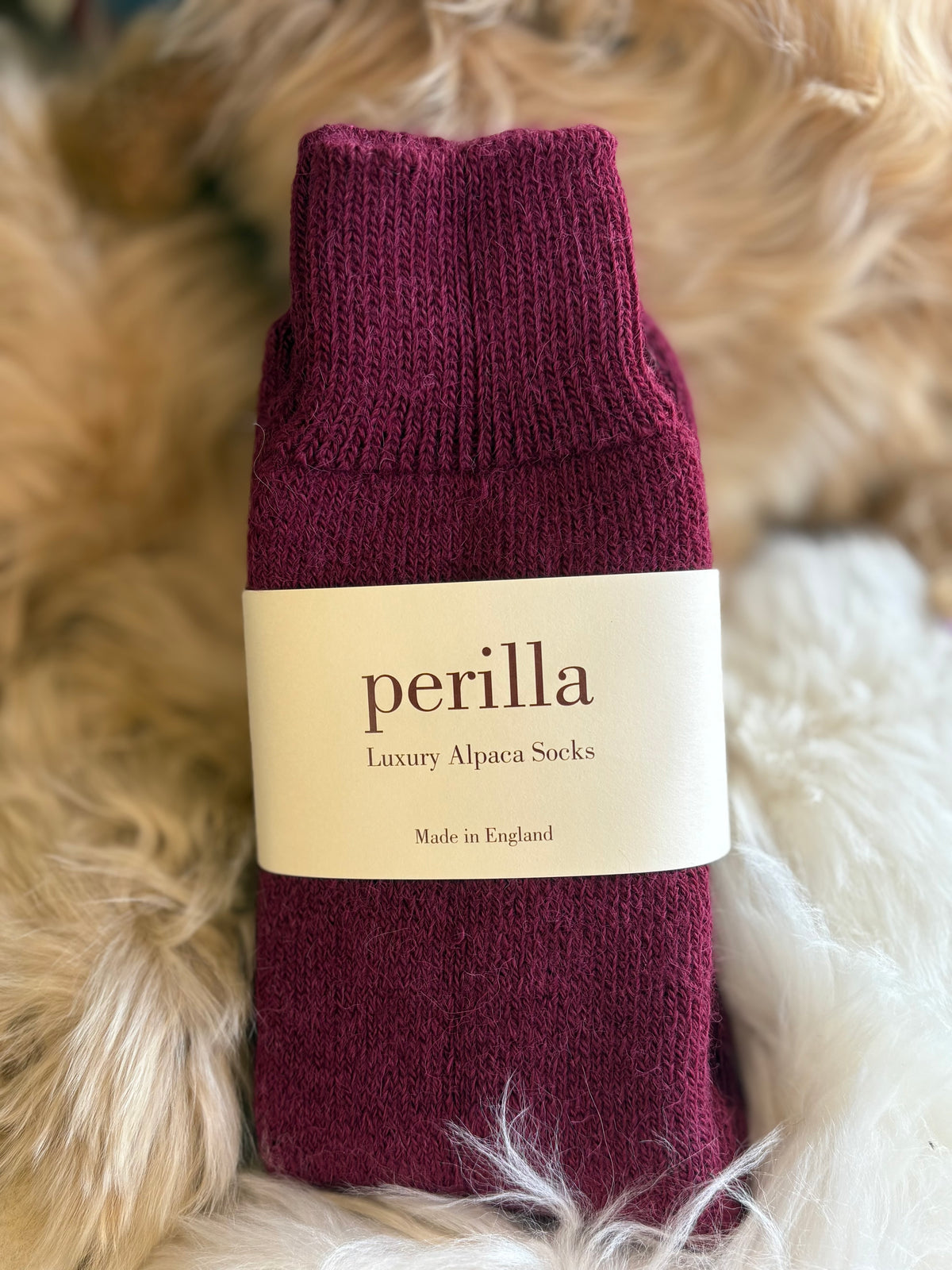Mulberry walking alpaca sock with 'perilla' label on a fluffy background