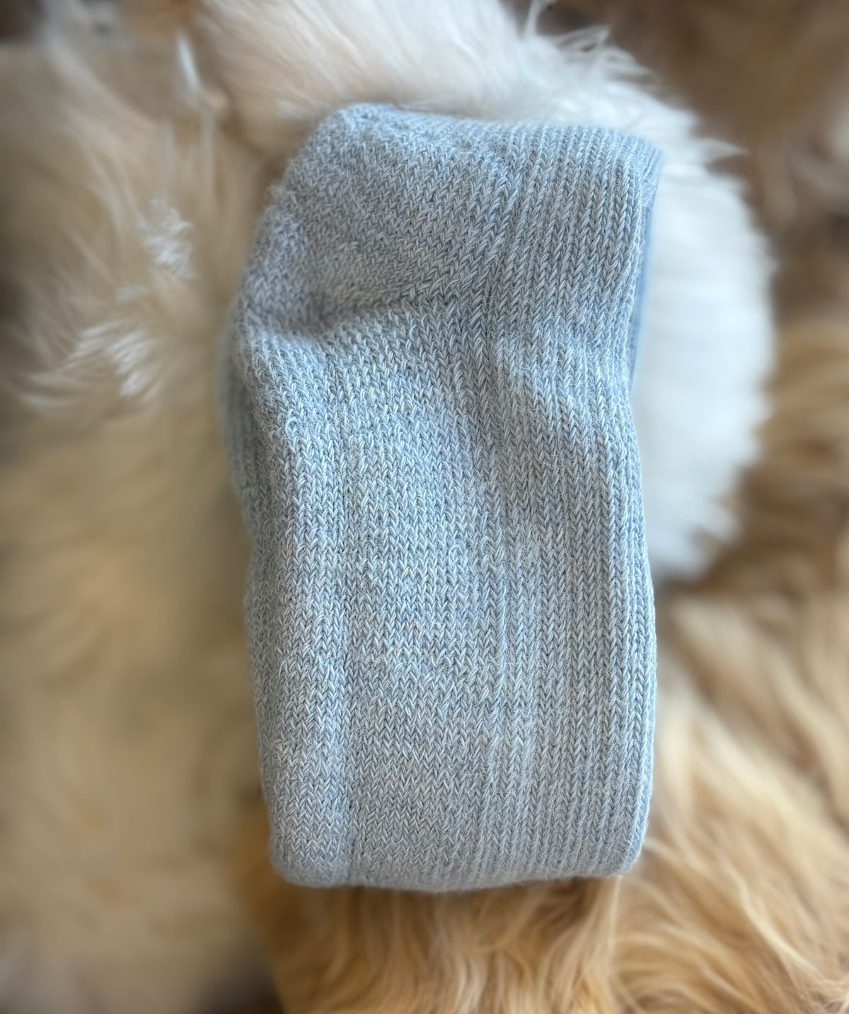 Pale Blue alpaca short ribbed sock on a fluffy white and beige surface
