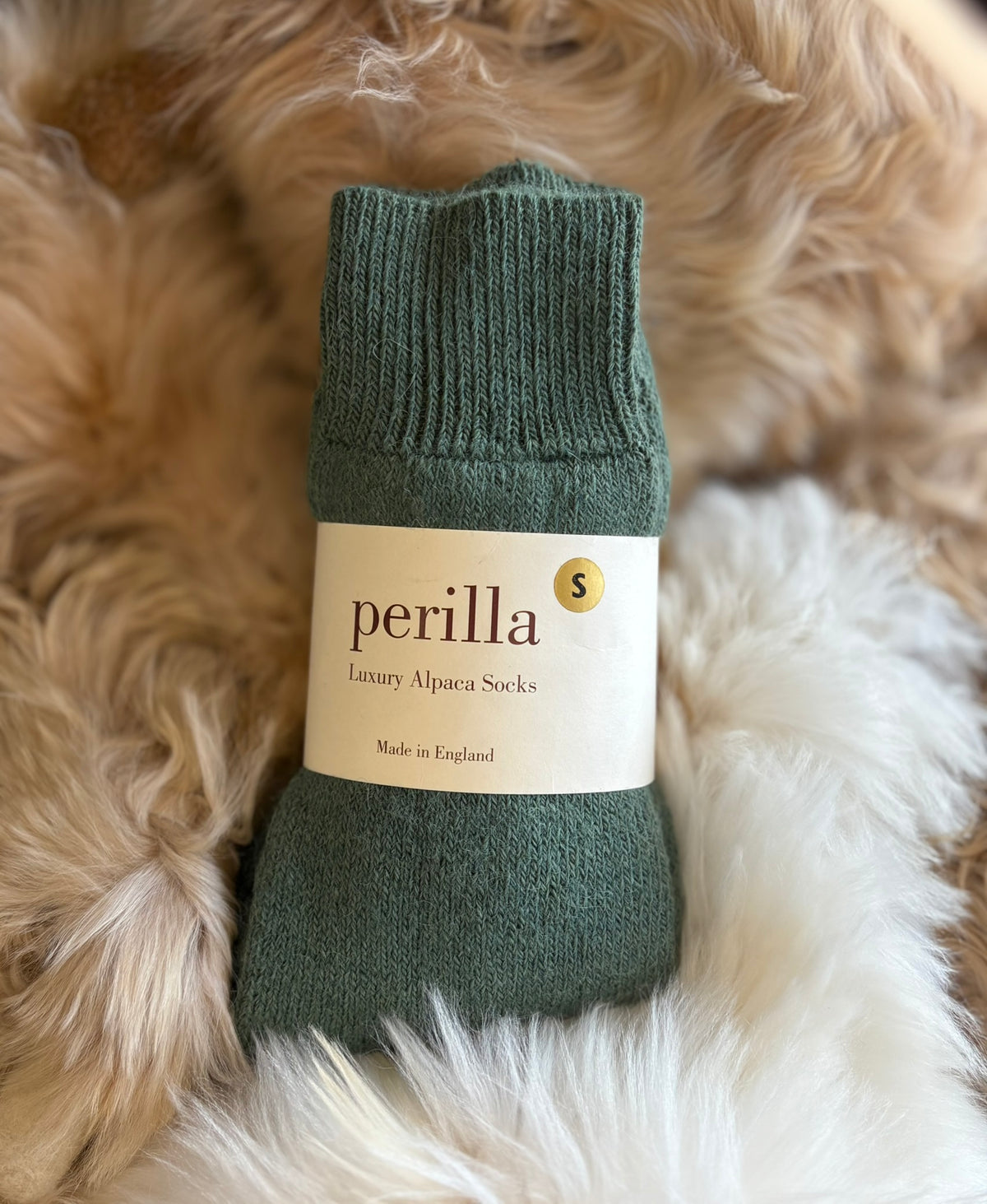 Sedge Green alpaca walking sock with 'perilla' label on a fluffy white and beige background