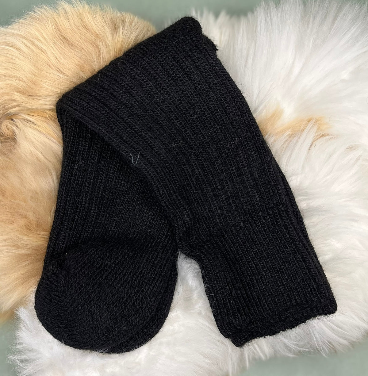 Black short ribbed alpaca socks on a fluffy white and beige surface