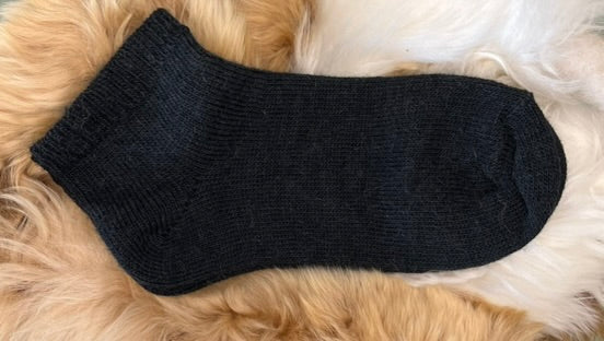 Black alpaca trainer sock on a fluffy fur surface