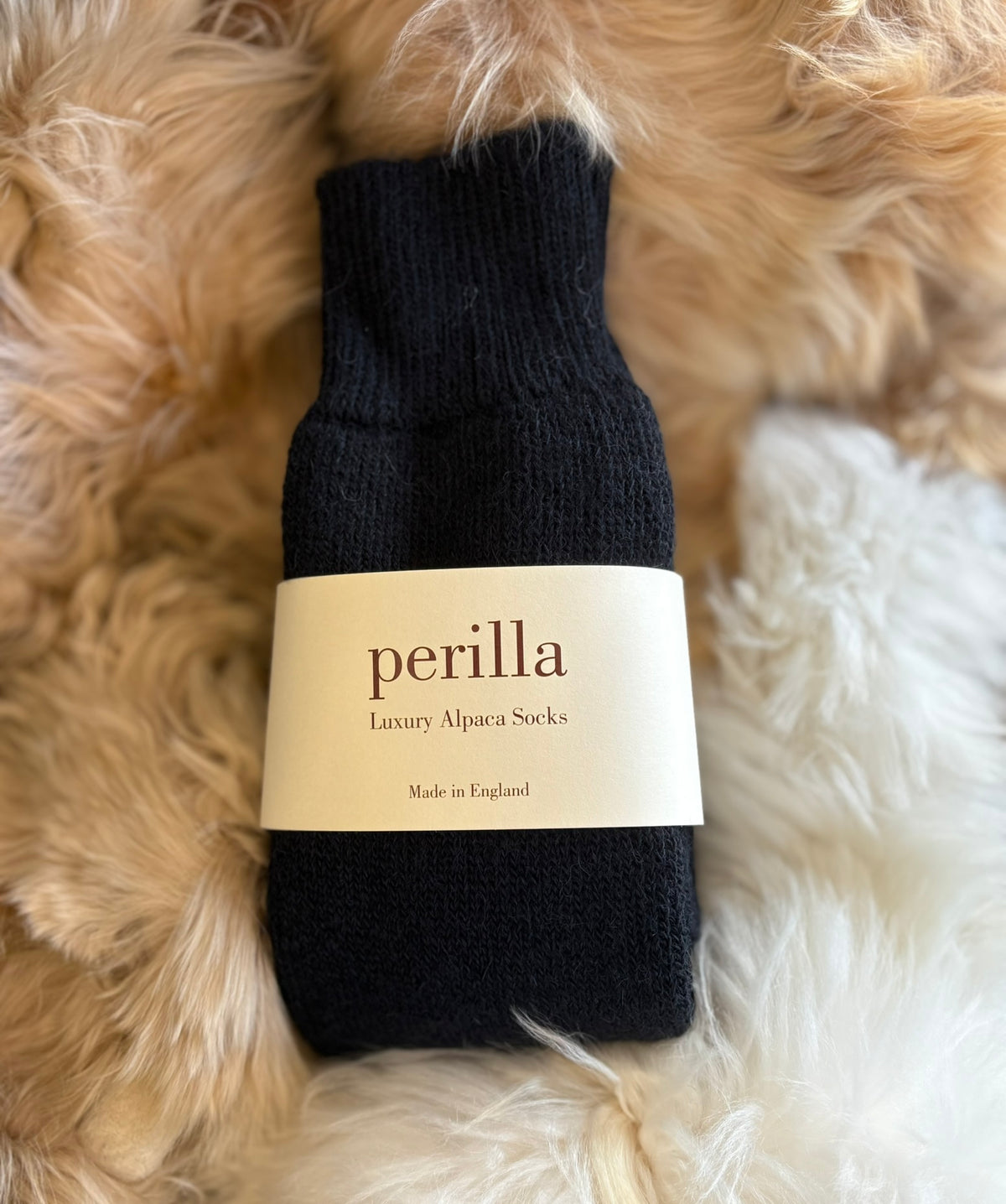 Black alpaca walking sock with 'perilla' label on a fluffy fur background