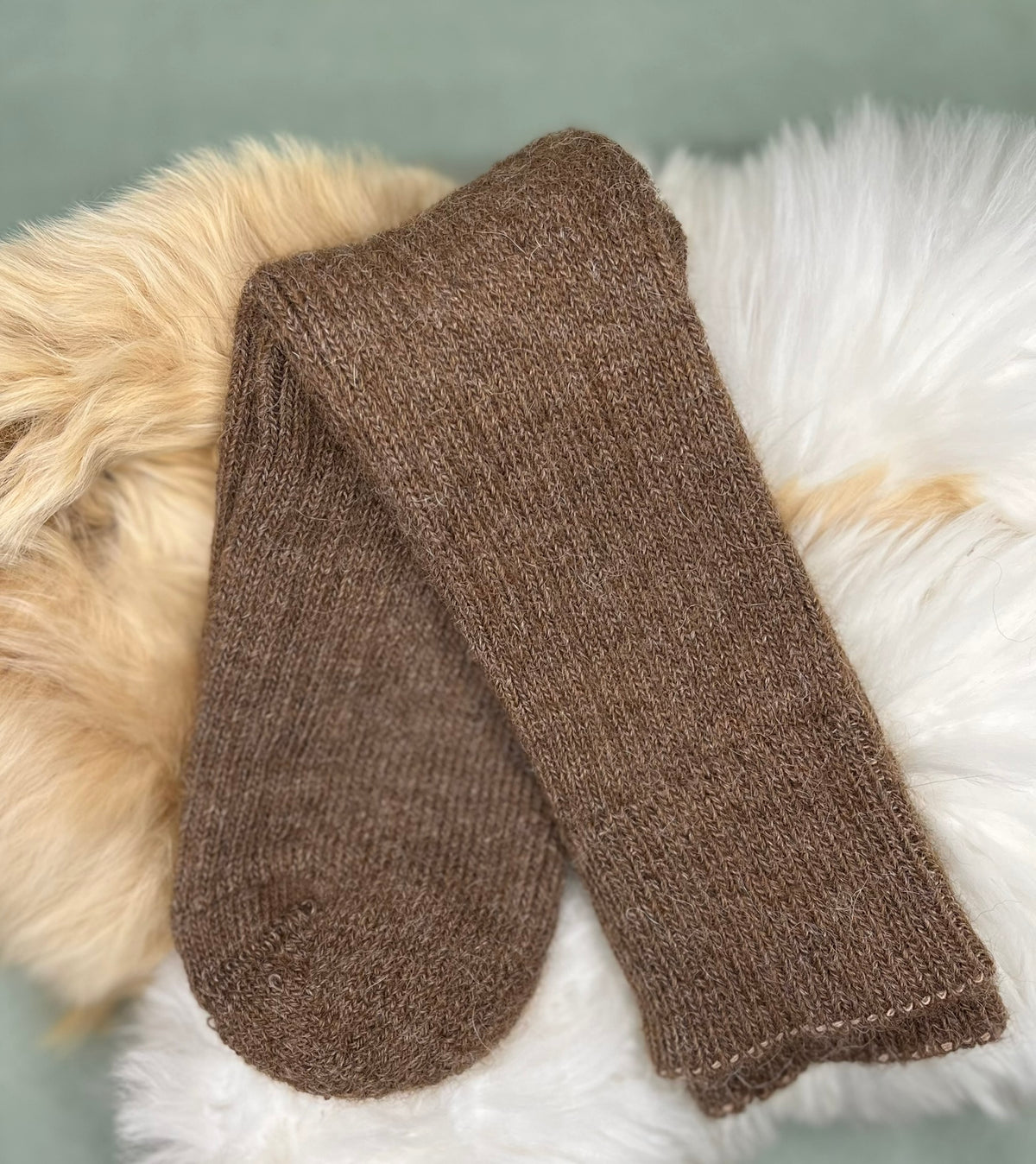 Brown alpaca short ribbed socks on a fluffy white surface with a grey background
