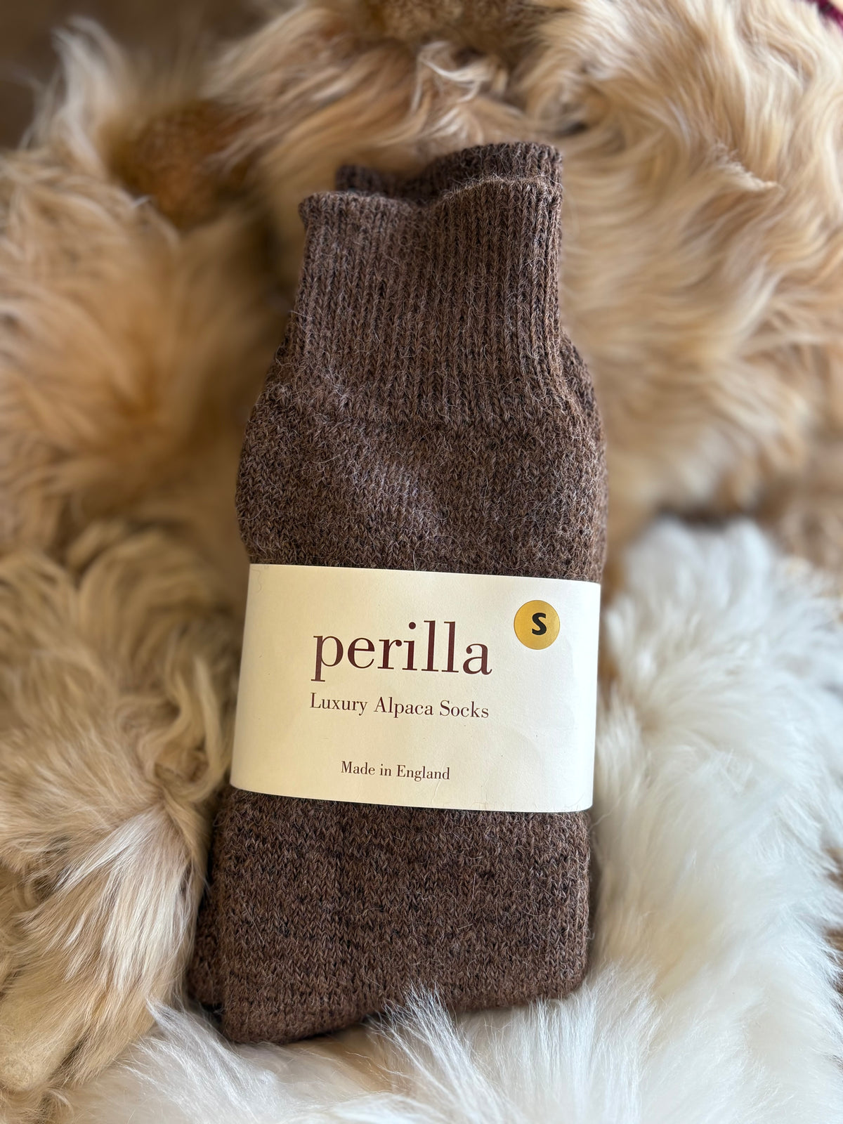 Brown walking alpaca sock with 'perilla' label on a fluffy white surface