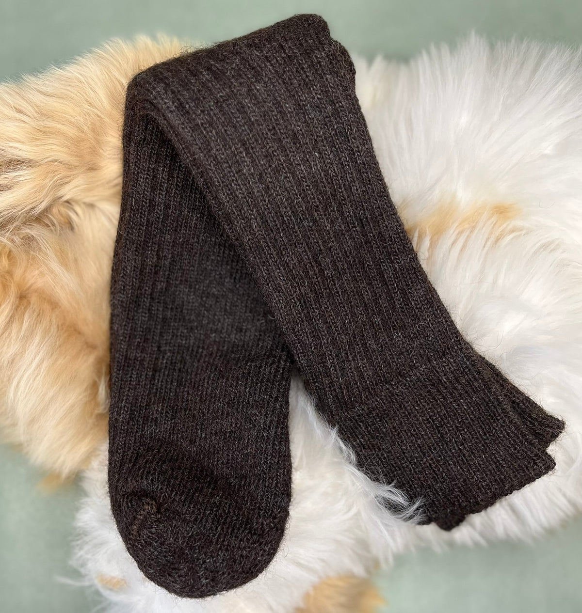 Charcoal short ribbed alpaca socks on a fluffy white surface with a light brown border.
