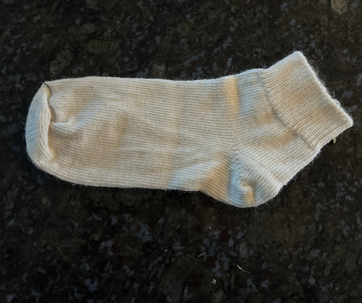 cream alpaca ankle sock on a dark textured surface