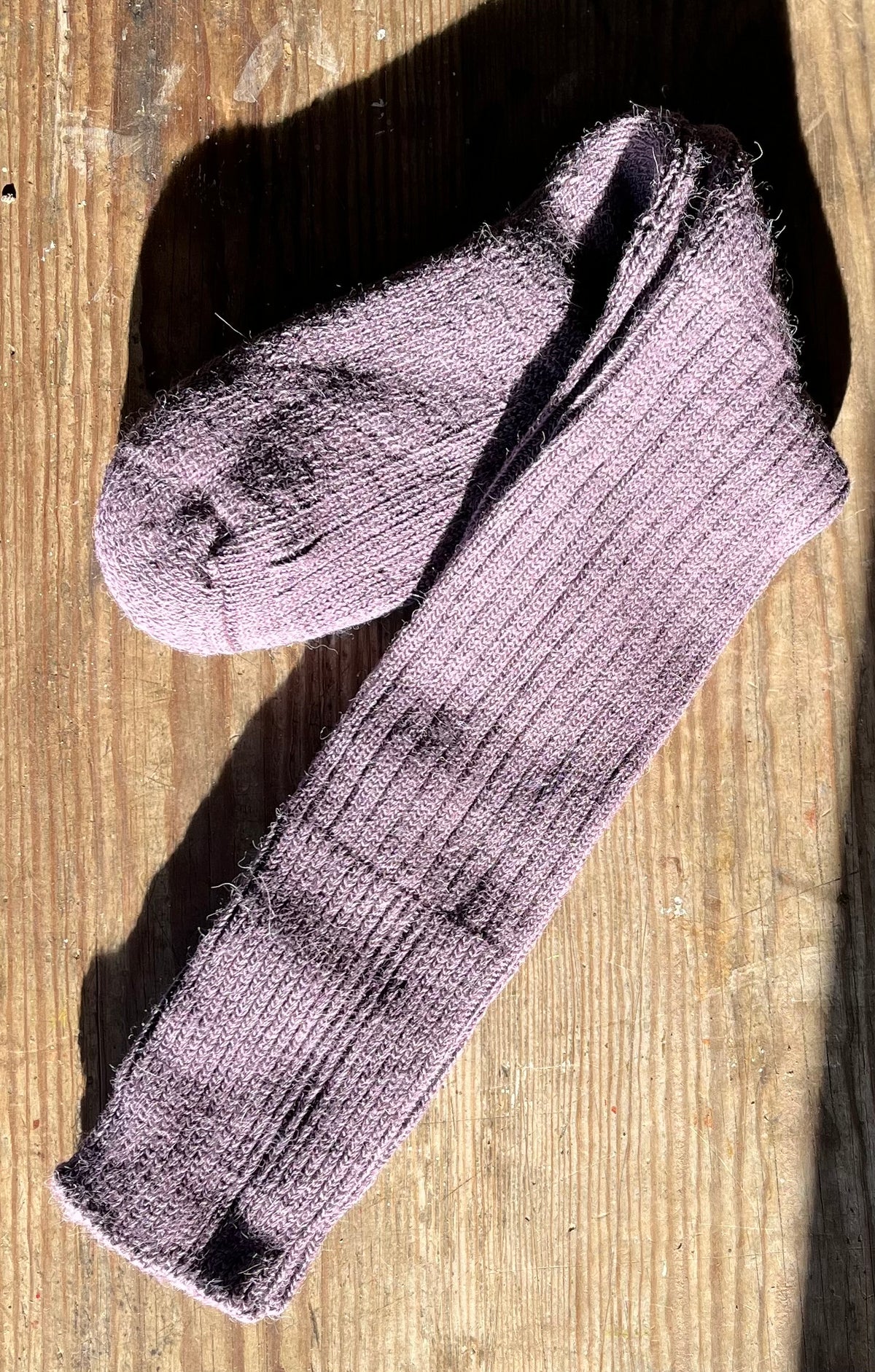 Pair of grape three quarter alpaca socks on a wooden surface
