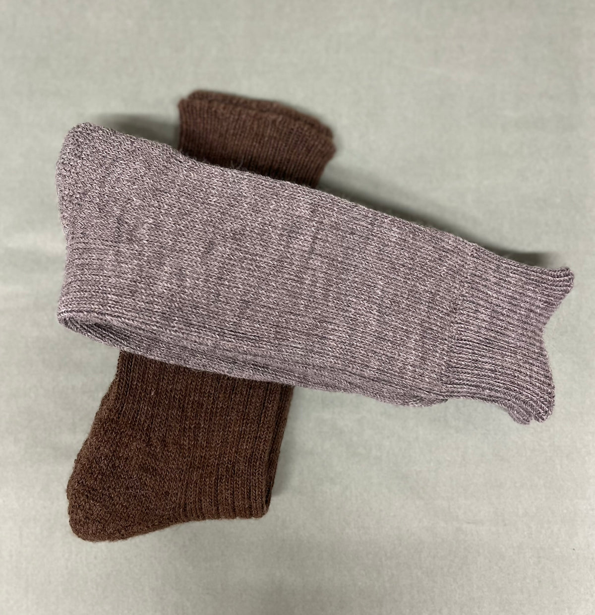 Two pairs of alpaca non-elasticated activity socks, one grey and one brown, on a light green background.