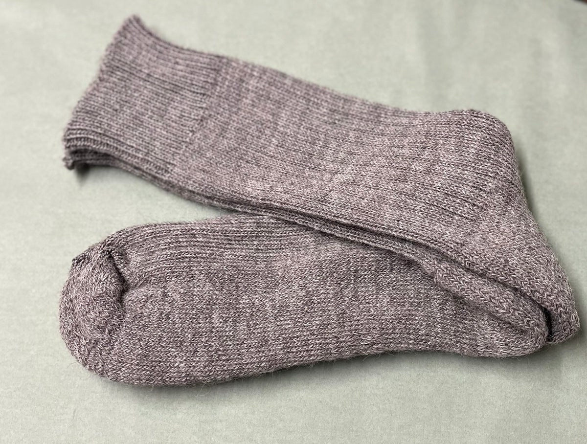 Pair of grey alpaca non-elasticated alpaca socks on a light green surface