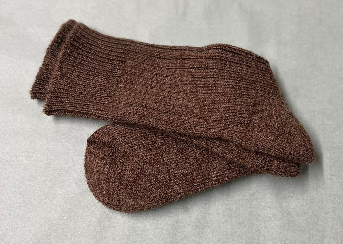 Pair of brown non-elasticated activity alpaca socks on a light green background