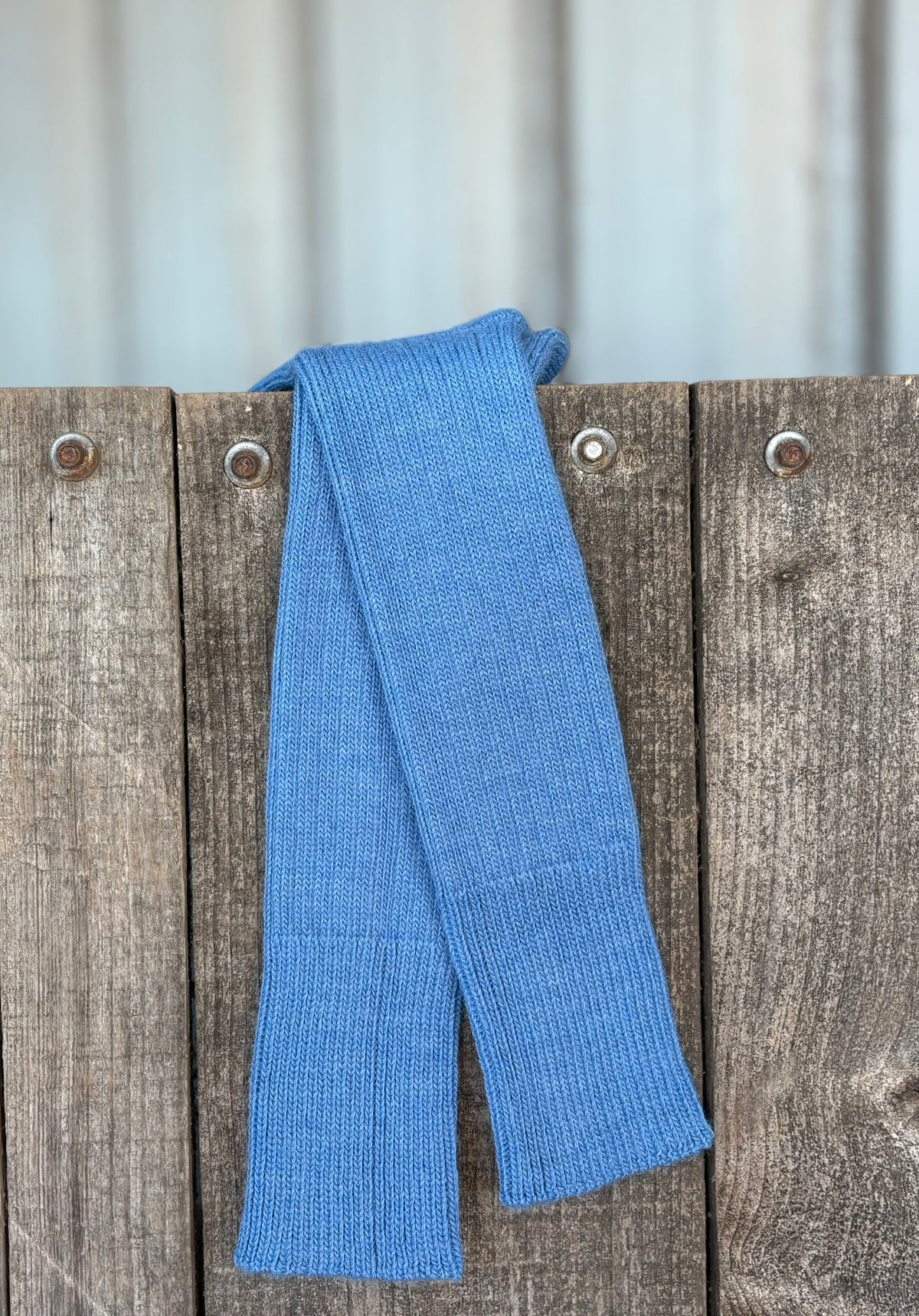 mid blue three quarter alpaca socks hanging on wooden gate
