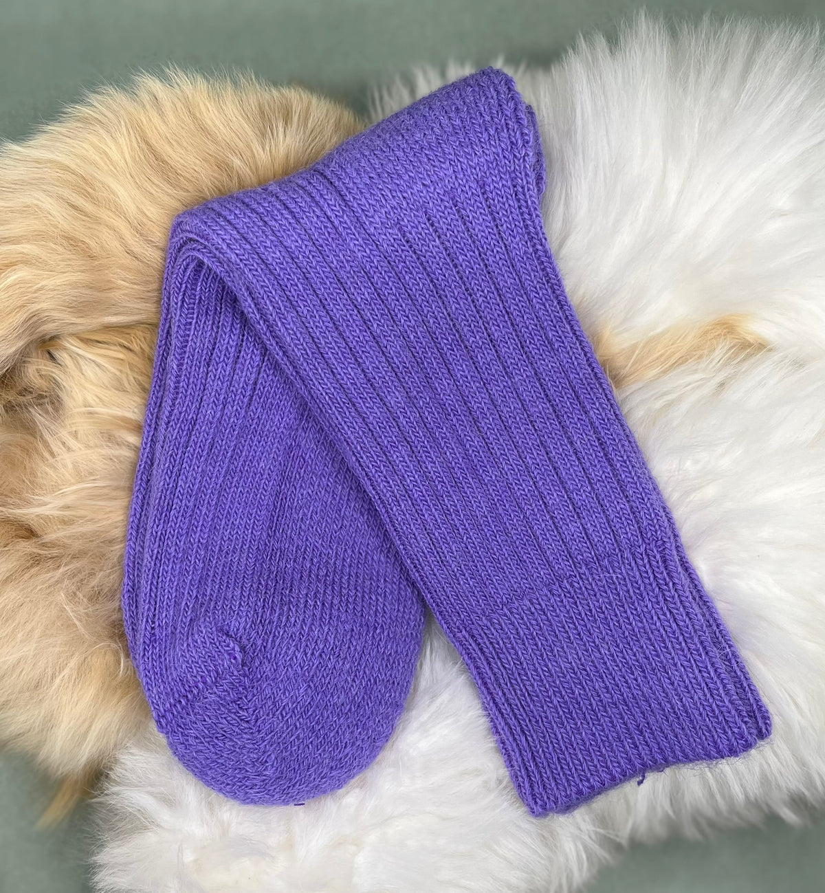 Purple alpaca short ribbed socks on a fluffy white and beige surface