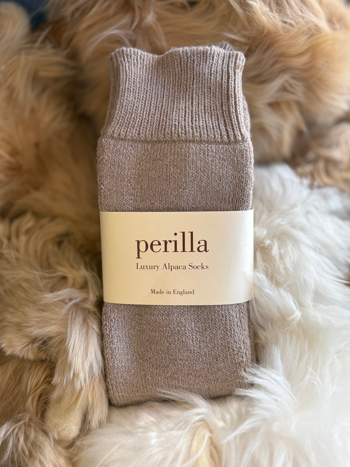 Taupe alpaca walking sock with 'perilla' label on a fluffy white surface